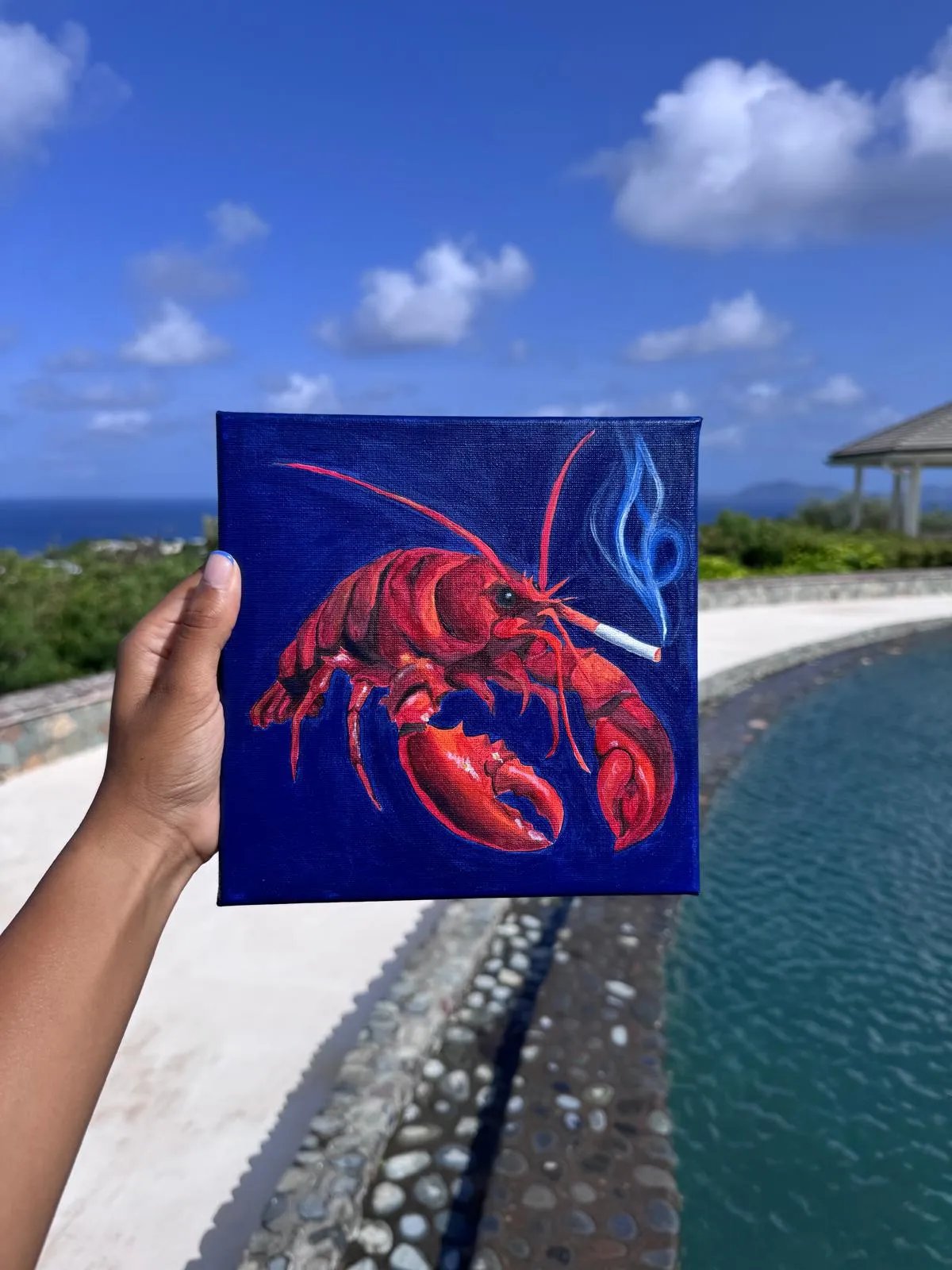 Smoking lobster on deep blue background being held in the sunlight next to swimming pool